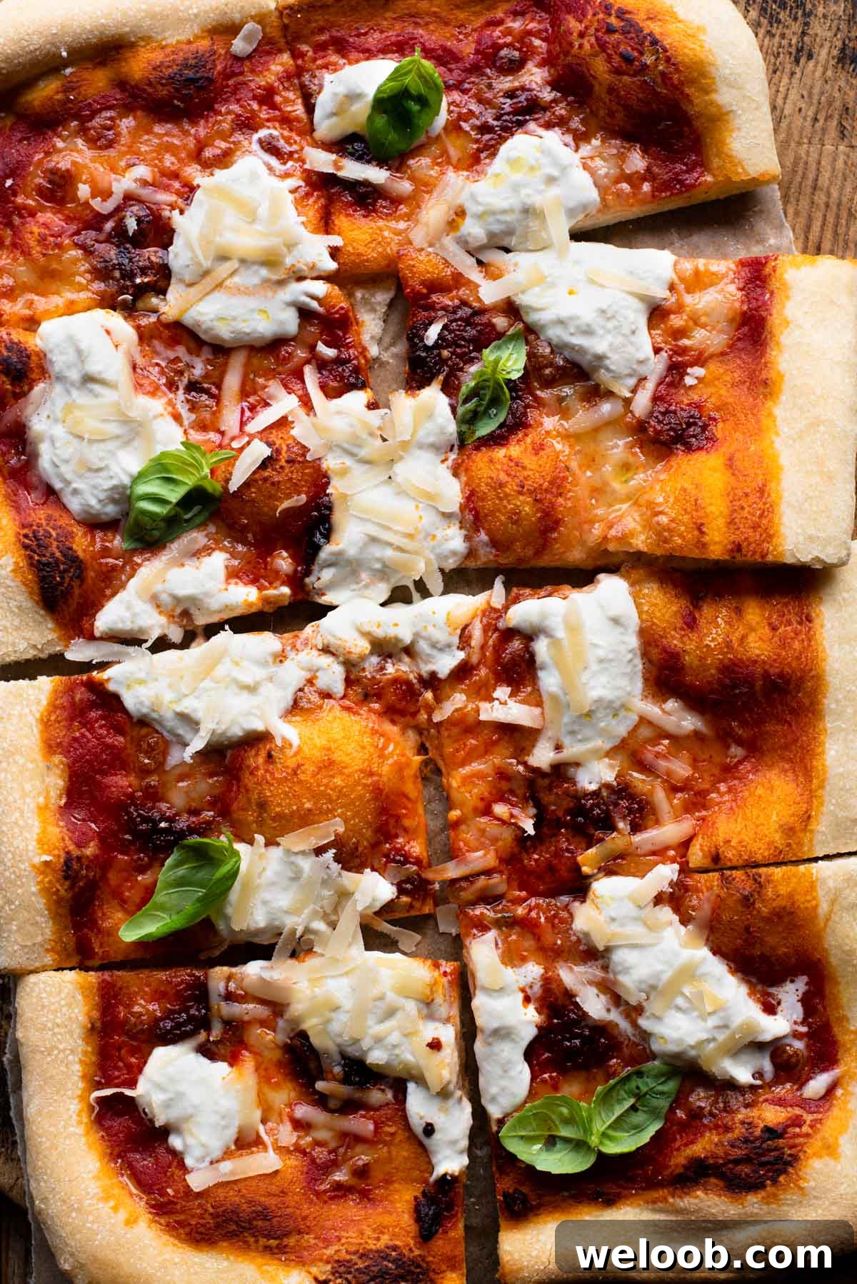 An overhead shot of a large Nduja pizza with burrata cheese and basil cut into 8 slices.