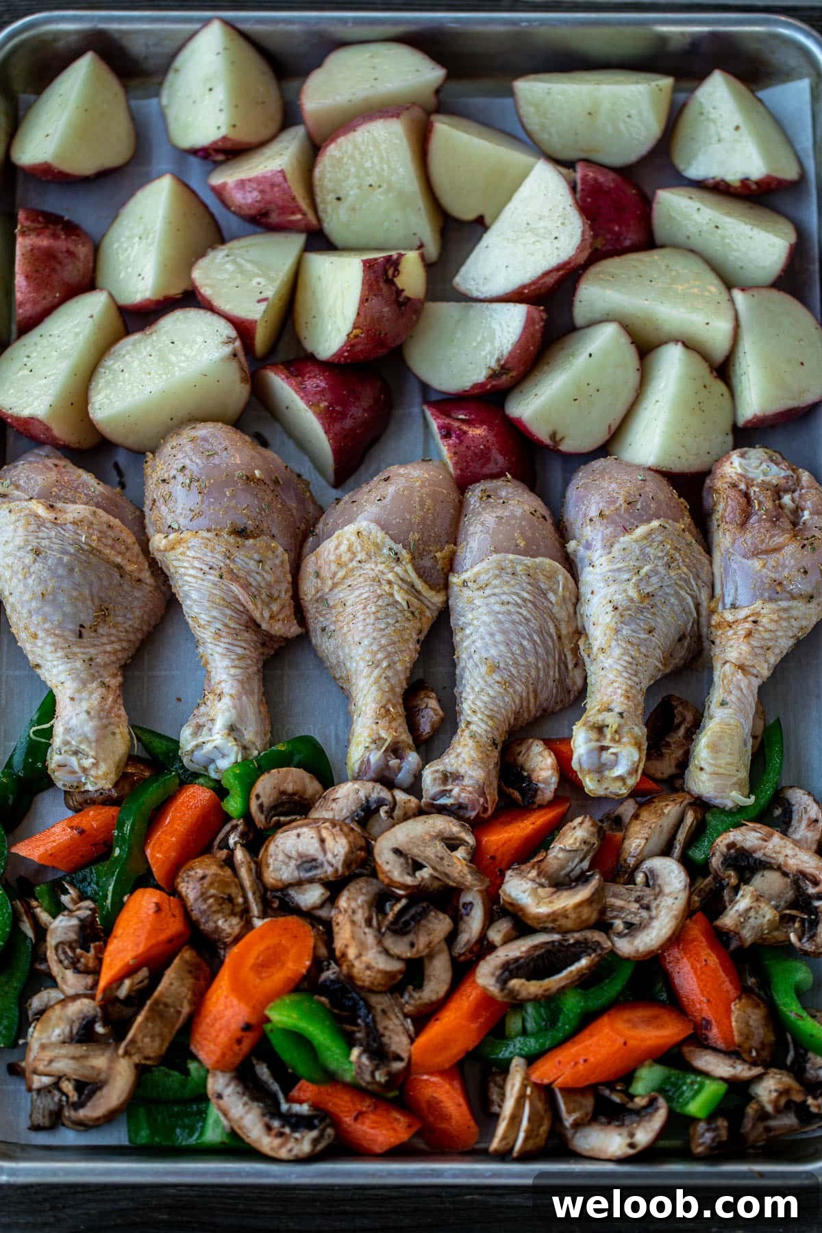 baking sheet lined with seasoned potatoes, chicken and veggies