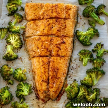Large salmon fillet and roasted broccoli on a sheet pan