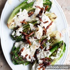 A close up of grilled romaine lettuce on a white plate topped with pancetta and Parmigiano Reggiano.