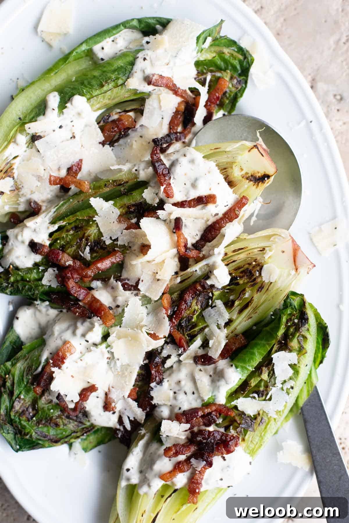 An overhead shot of grilled romaine lettuce topped with pancetta and a creamy dressing.