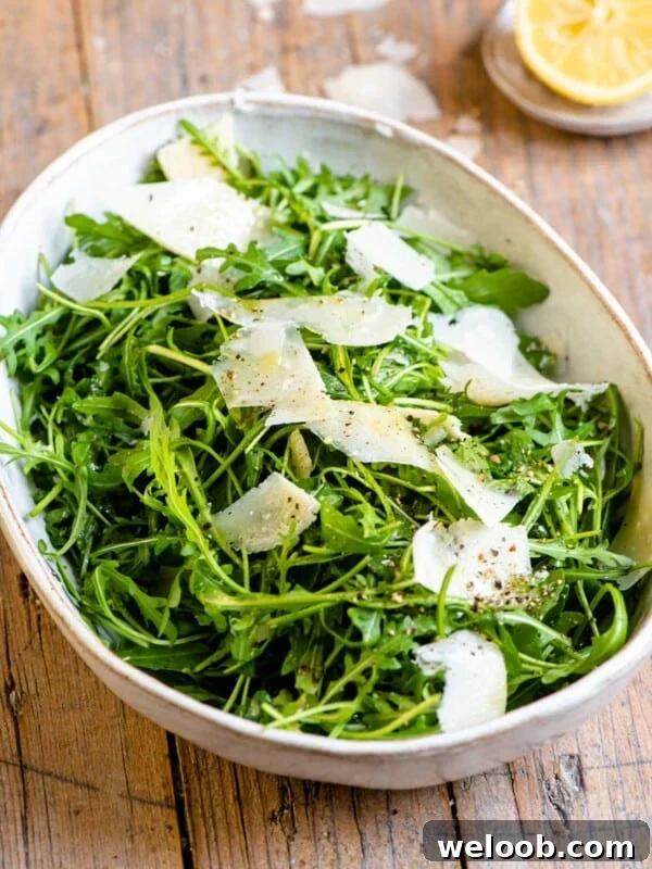 An arugula salad in a large serving bowl with shavings of parmesan