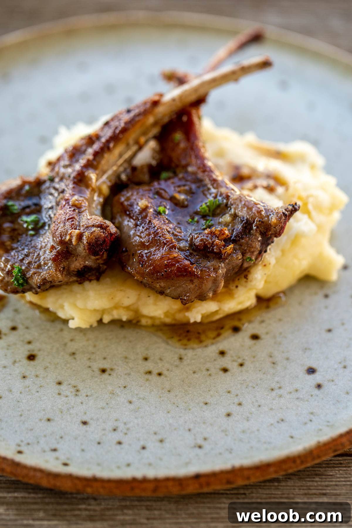 A plate with mashed potatoes and lamb chops.