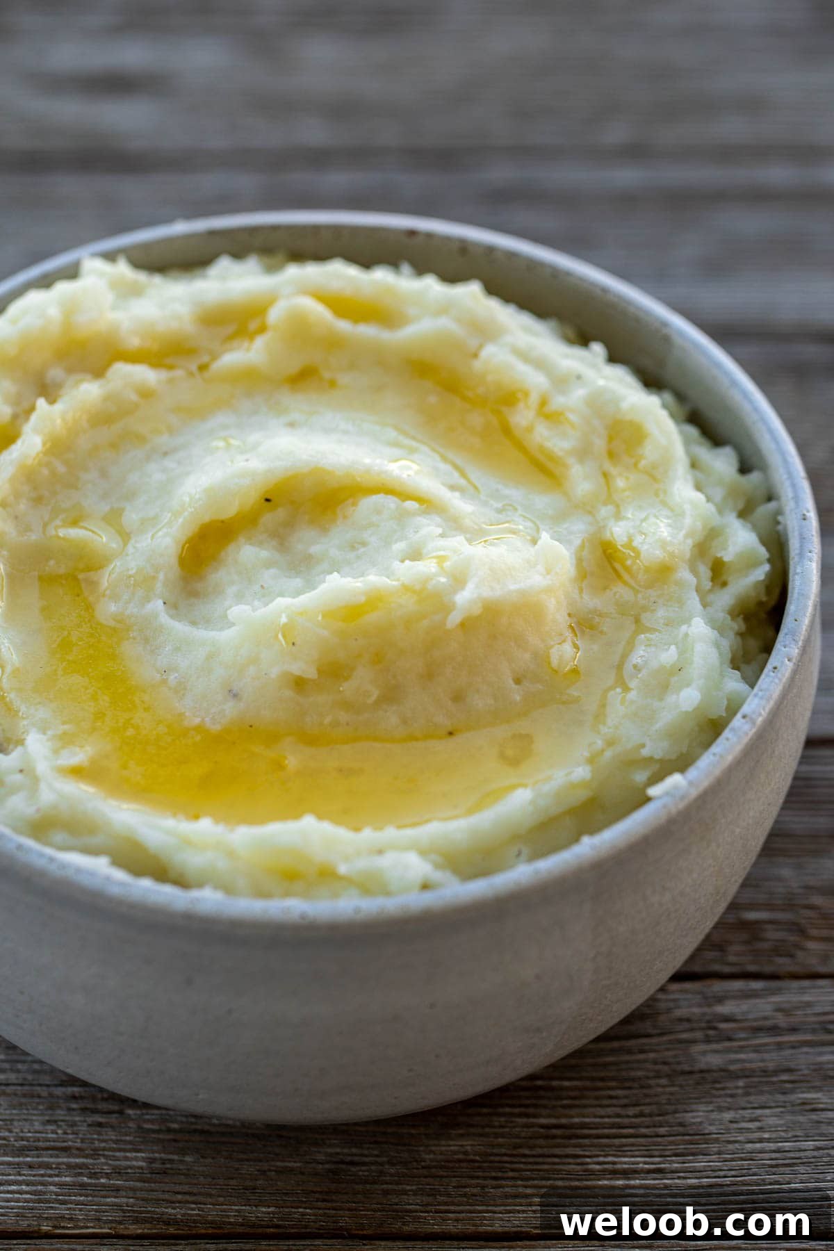 A bowl of creamy mashed potatoes topped with melted butter