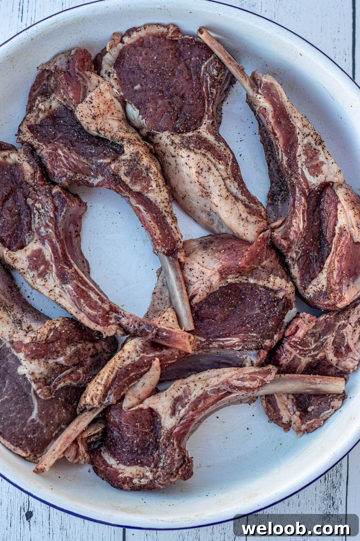 Seasoned lamb chops in a white bowl.