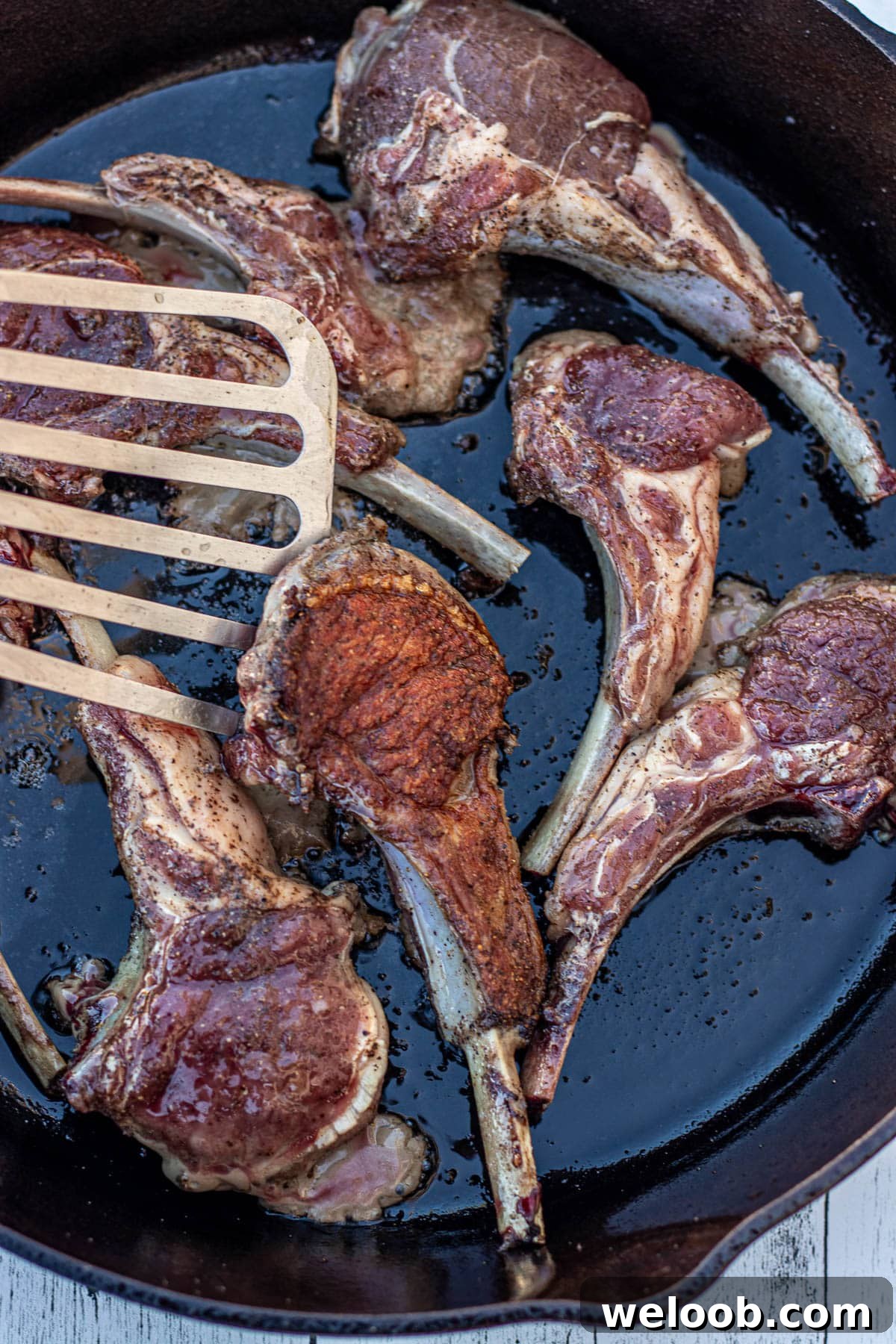 A fish spatula flipping a lamb chop.