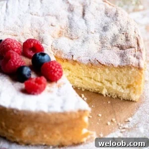 A square image of an Italian sponge cake (Pan di Spagna) close up with a slice cut out and berries on top.