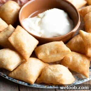 A close up square image of Gnocco Fritto (Italian fried dough) on a plate with cheese.