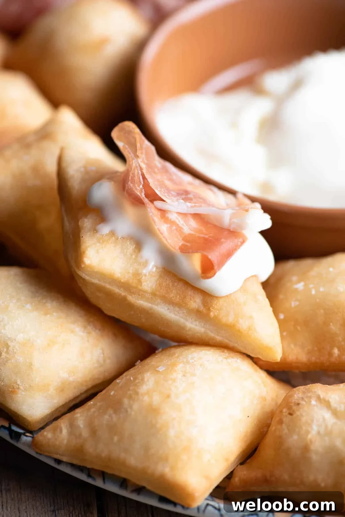 A close up of Gnocco Fritto (Italian fried dough) with cheese and prosciutto on top.