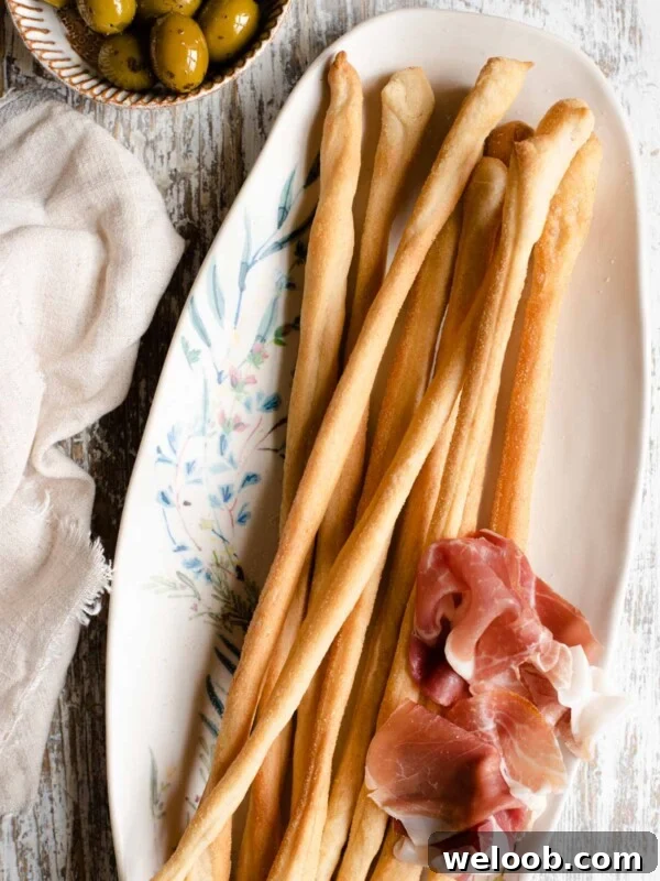 An overhead shot of Italian Grissini on a serving plate with olives at the side