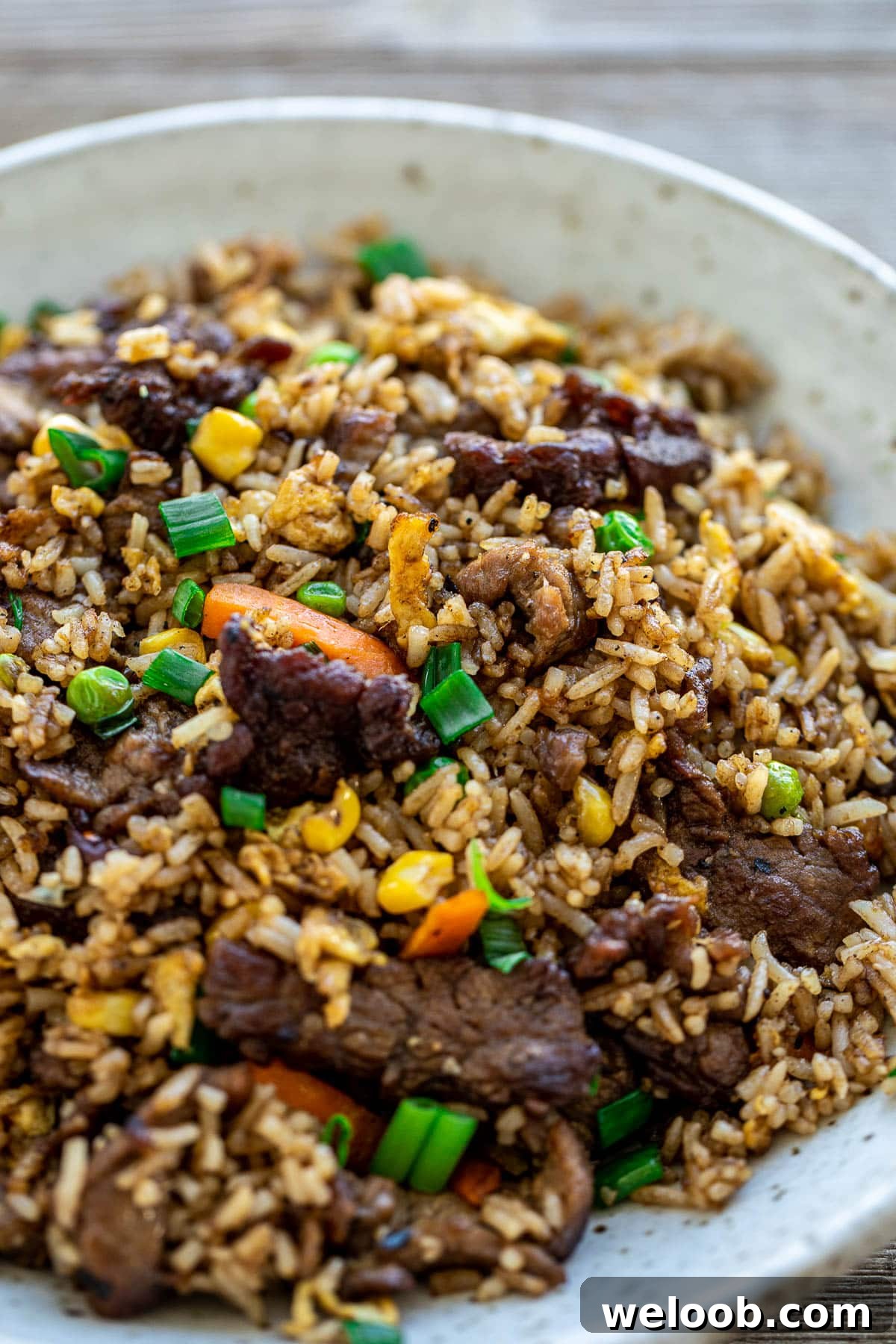 Fried rice in a bowl with veggies garnished with green onions.