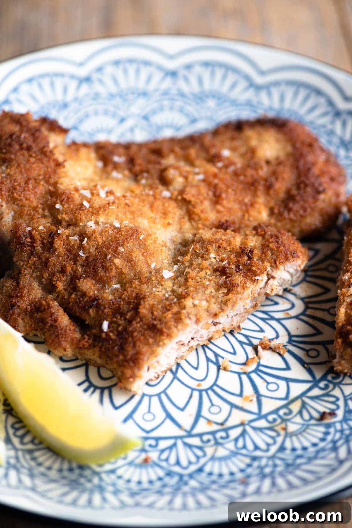 A close up of Veal Milanese on a plate with a slice cut.