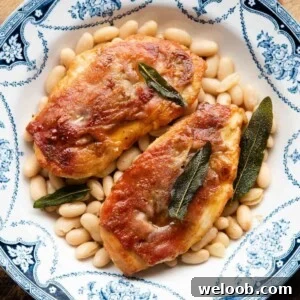 A cropped square image of chicken saltimbocca in a blue bowl on top of cannellini beans.