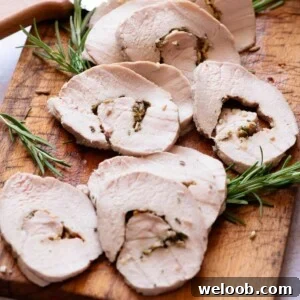 A close up cropped image of roast pork loin sliced on a wooden board.
