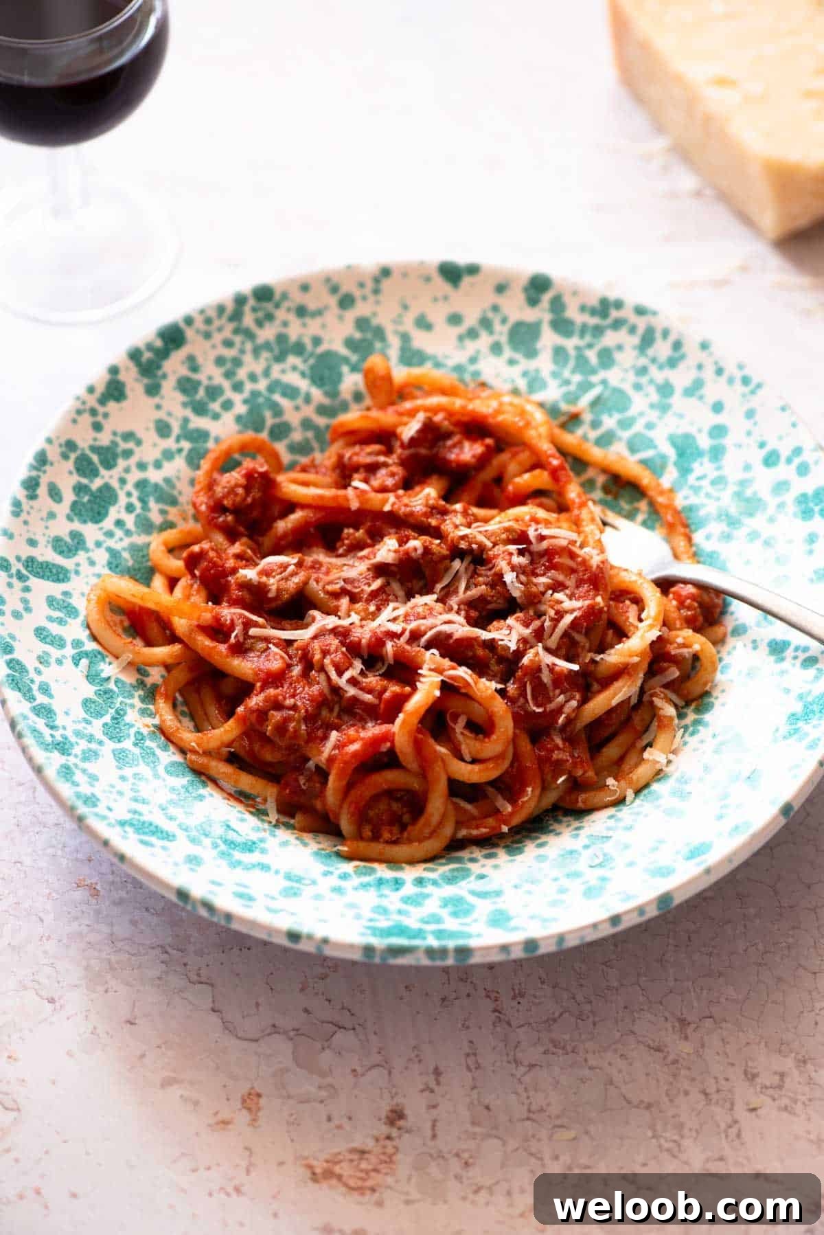 Tuscan sausage pasta with pici in a blue bowl on a light work surface.