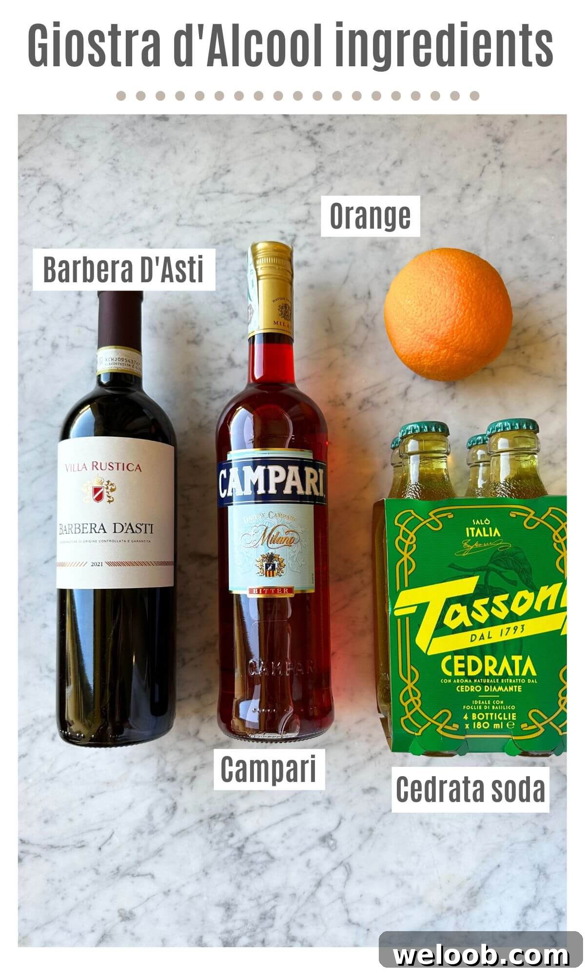 An overhead shot showing all the ingredients to make an Italian red wine spritz; Barbera D'Asti, Campari, Cedrata soda and an orange on a marble worktop.