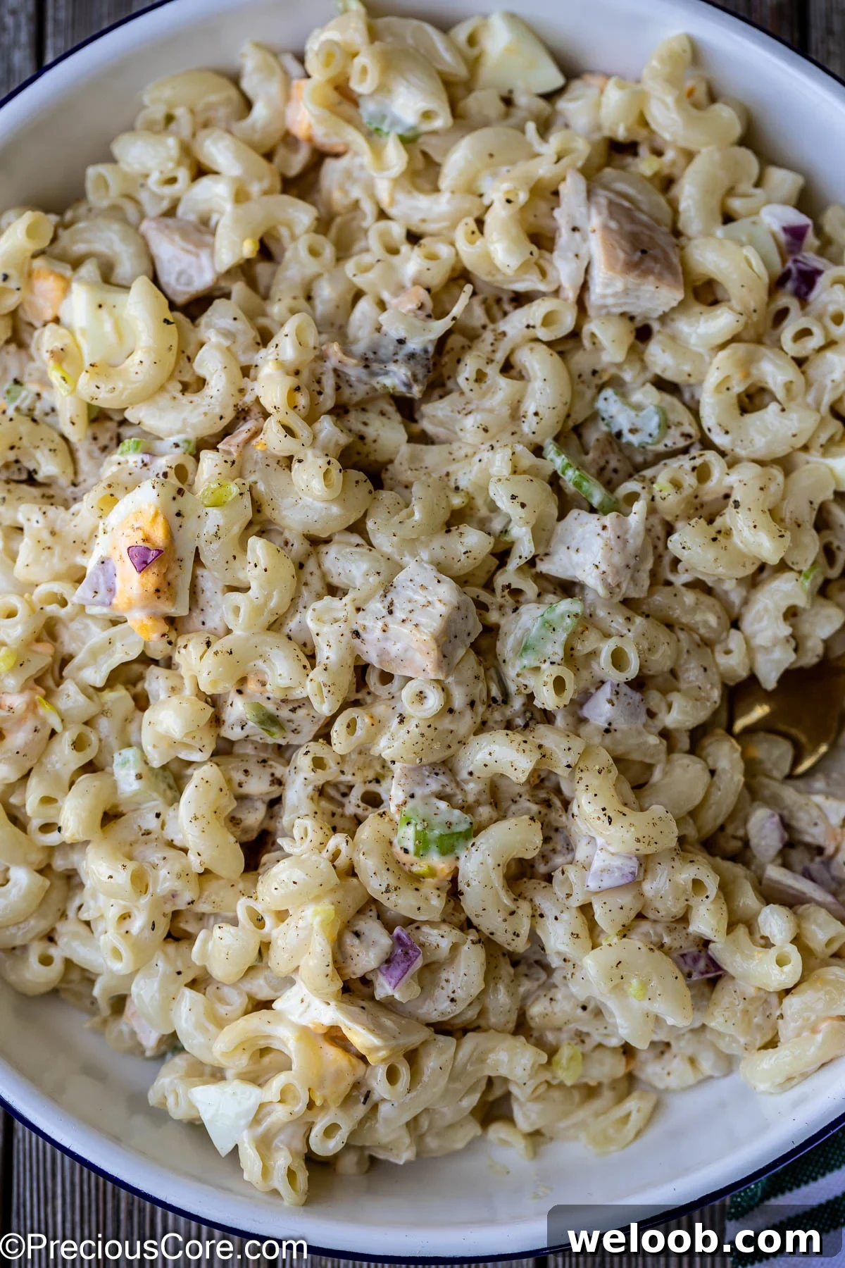 ,Macaroni salad with chicken in a white bowl.