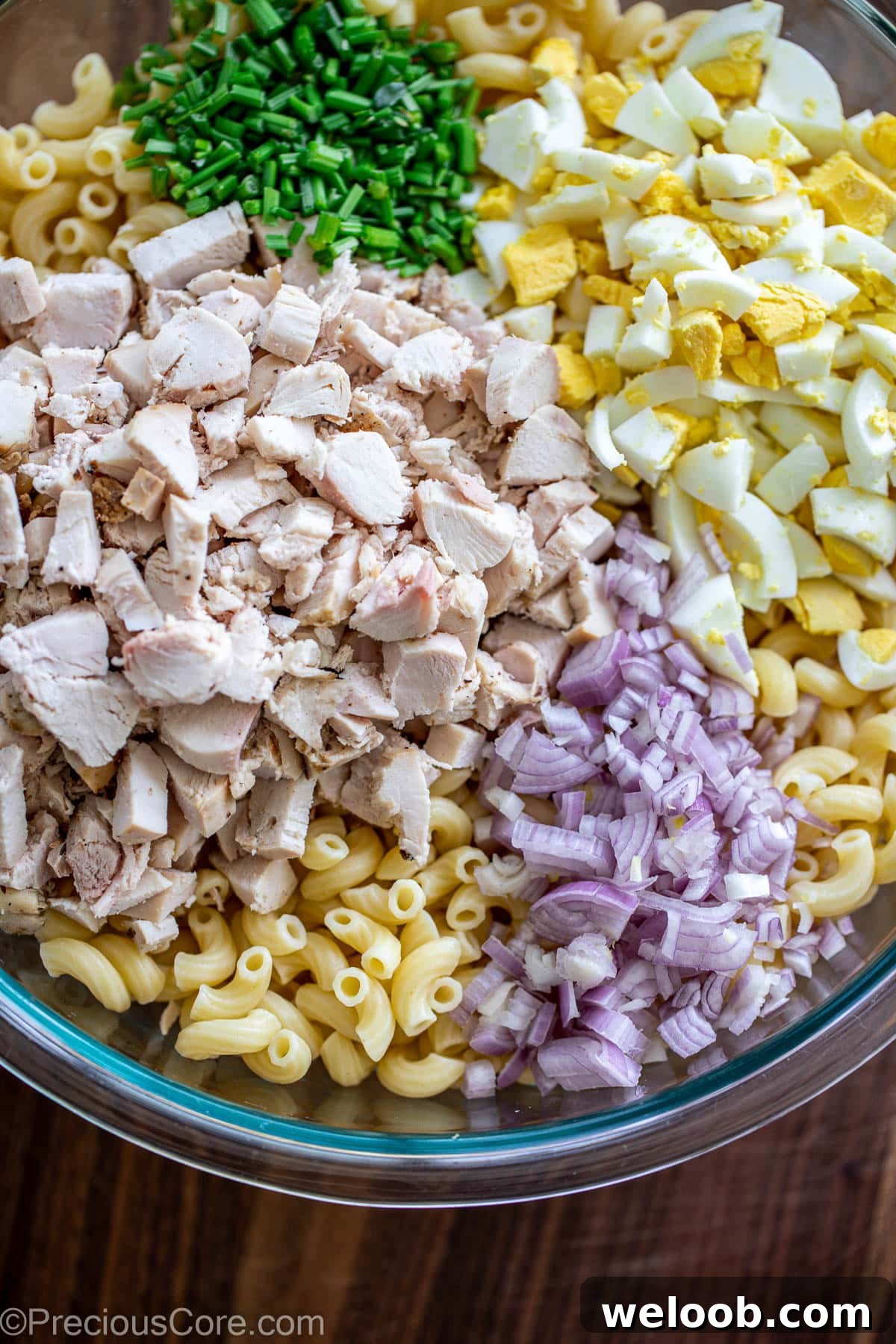 Ingredients for macaroni chicken salad in a large bowl.