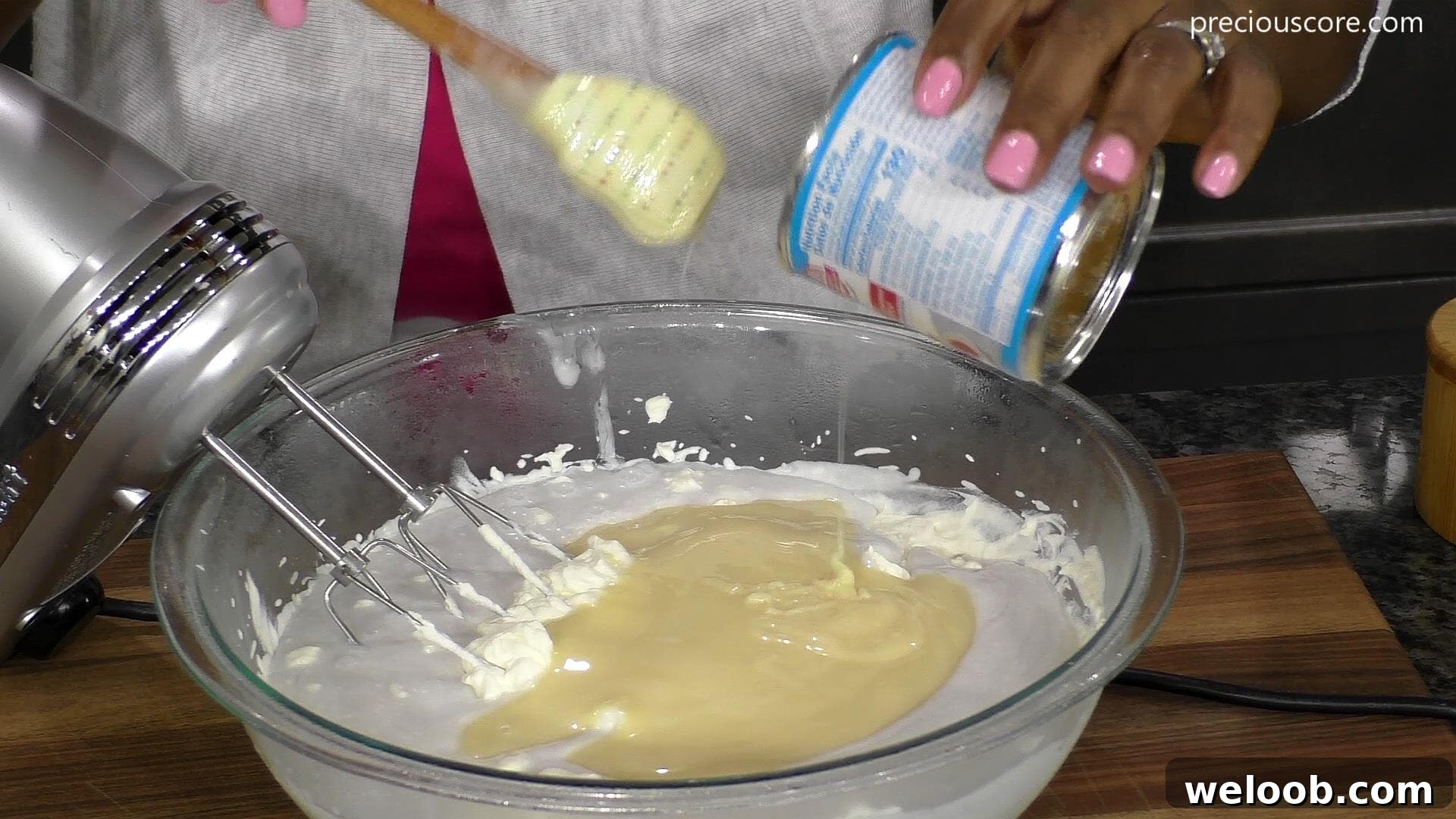 Sweetened condensed milk pouring from can into bowl.