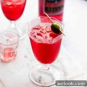 A cropped image of a Select Spritz on a marble surface garnished with a green olive.