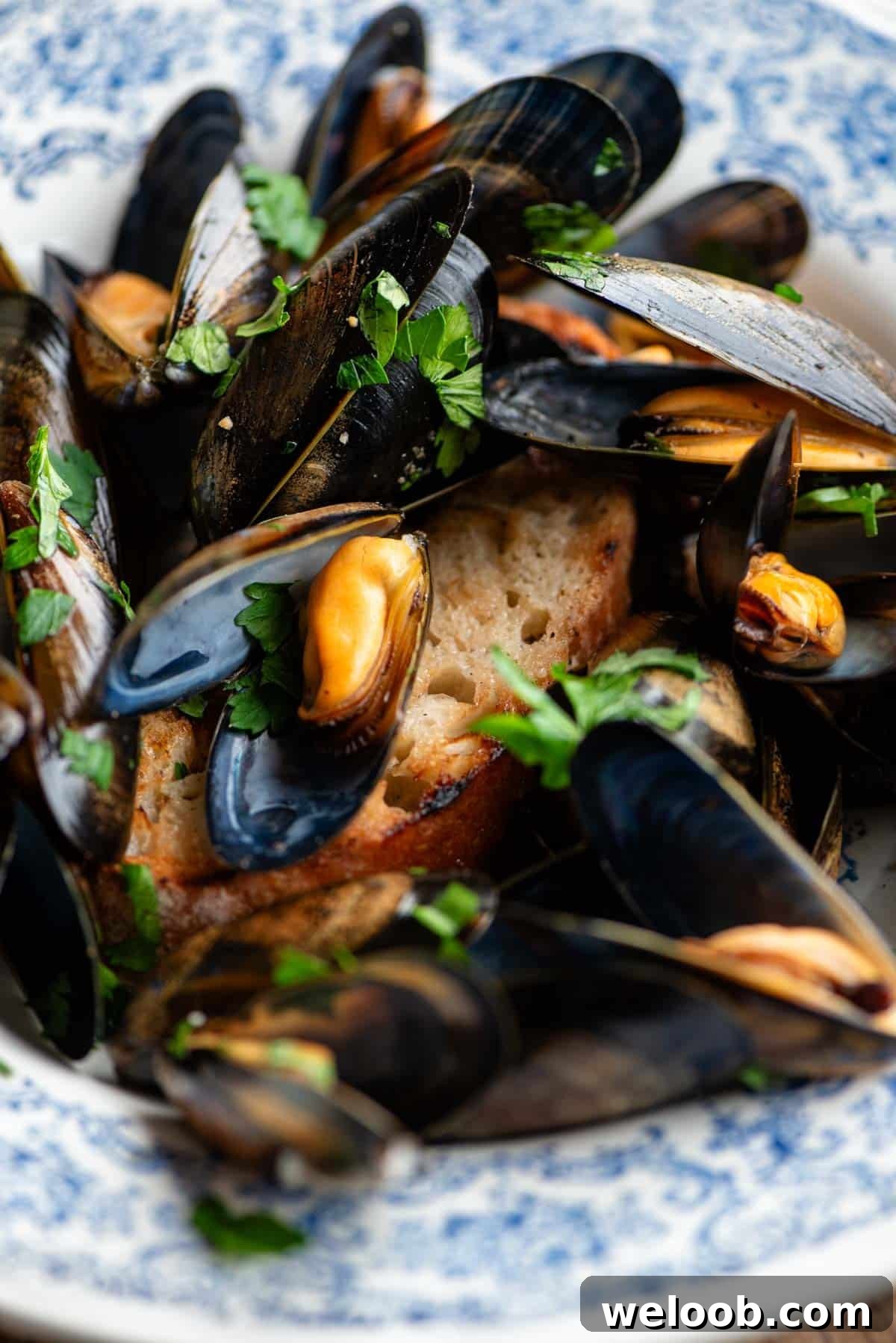 A close up of peppered mussels on top of a piece of ciabatta bread.