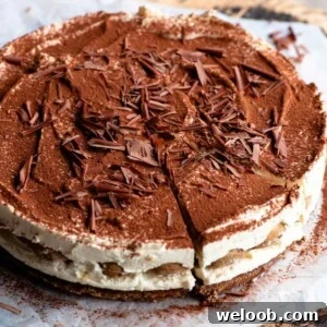 A close up of a tiramisu cheesecake on a wooden board dusted with cocoa powder.