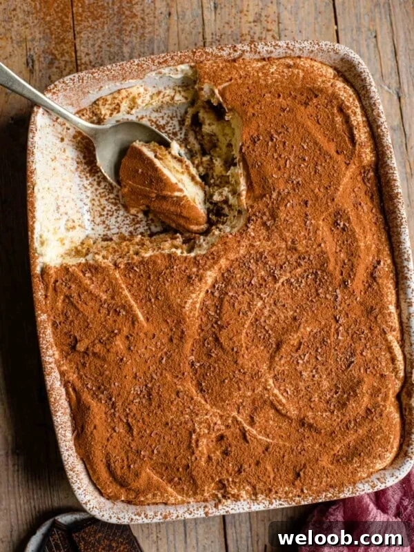 an overhead shot of a tiramisu in a dish with a slice out