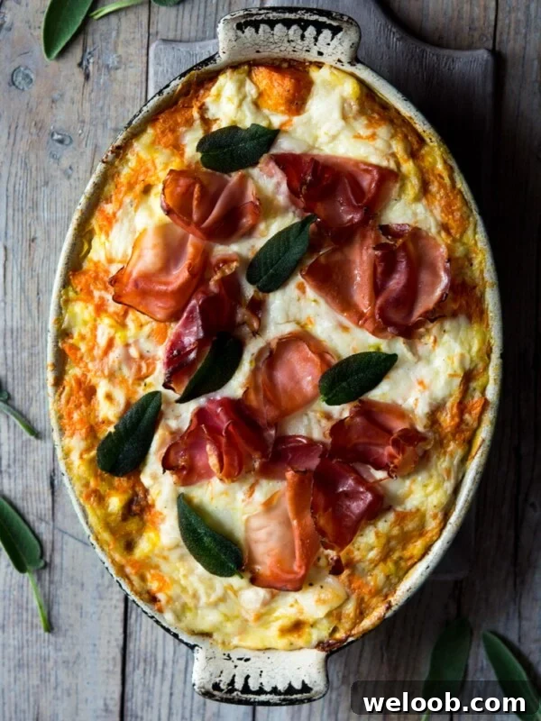 butternut squash lasagna in an oval baking dish on a wooden surface