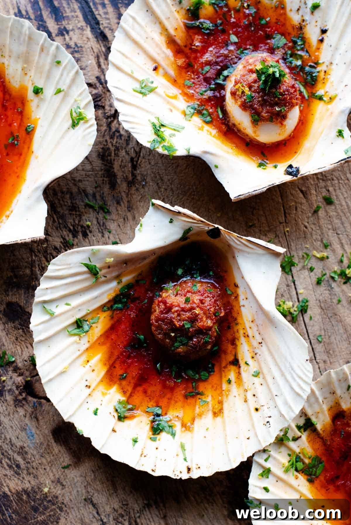 An overhead shot of scallops in their shells with a Nduja garlic butter on top.