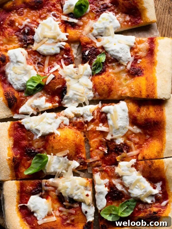 An overhead shot of a large Nduja pizza with burrata cheese and basil cut into 8 slices.