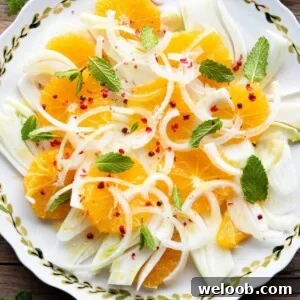 A close up overhead shot of a fennel and orange salad with pink peppercorns.
