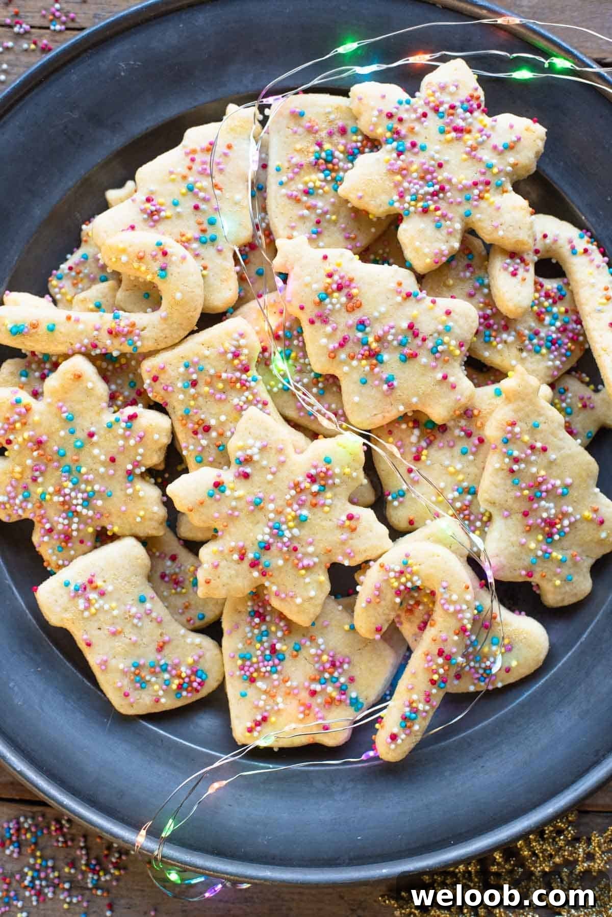 An overhead shot of Befanini Tuscan Christmas cookies cut into Christmas shapes on a plate topped with spinkles.