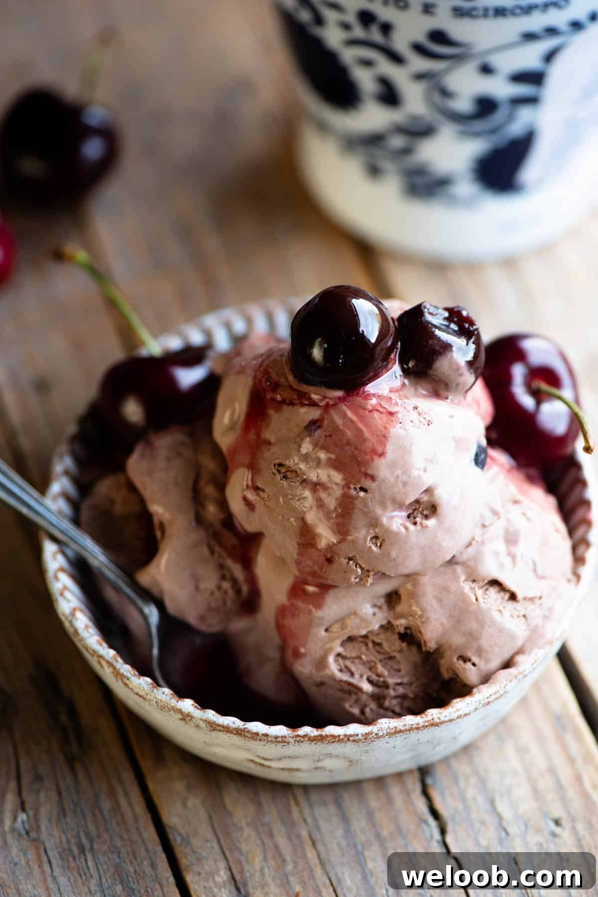 A close up of three scoops of cherry chocolate ice cream in a small dish topped with cherries.