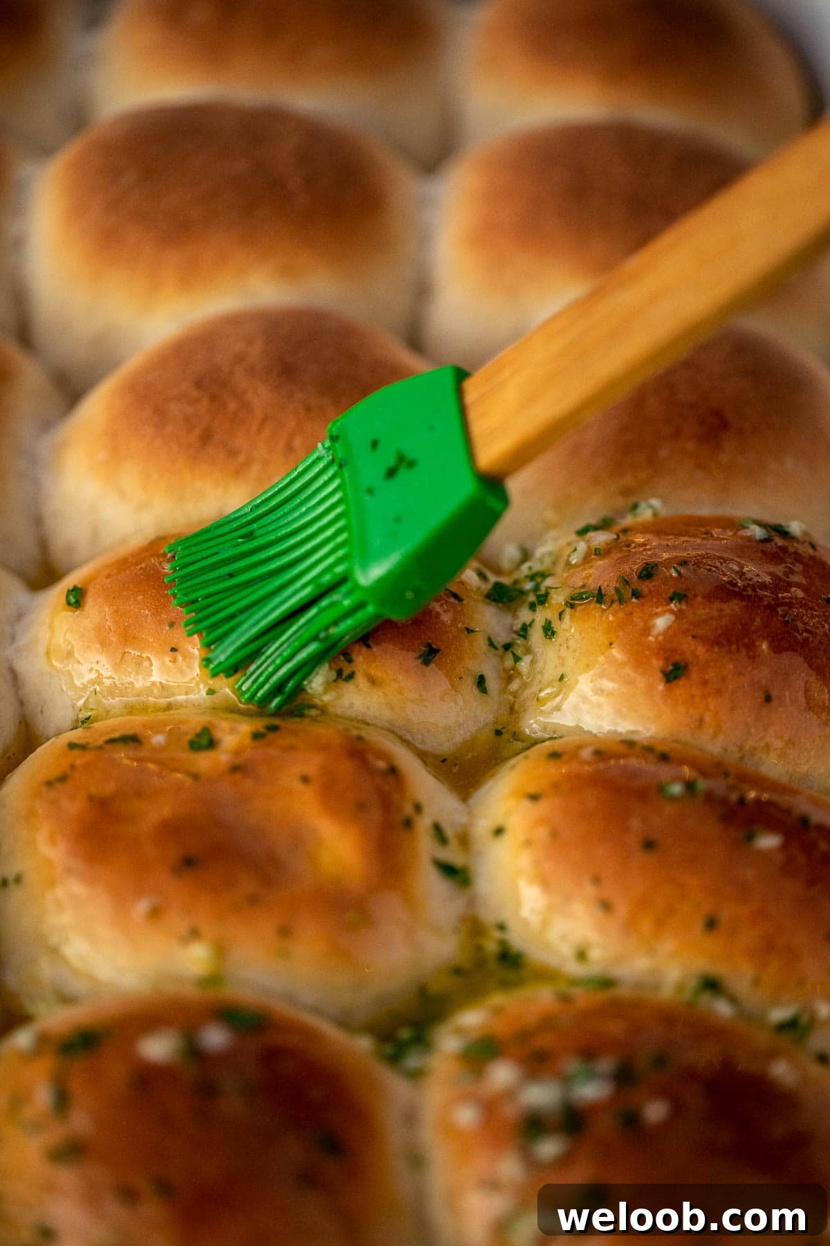 Brushing garlic butter over dinner rolls.