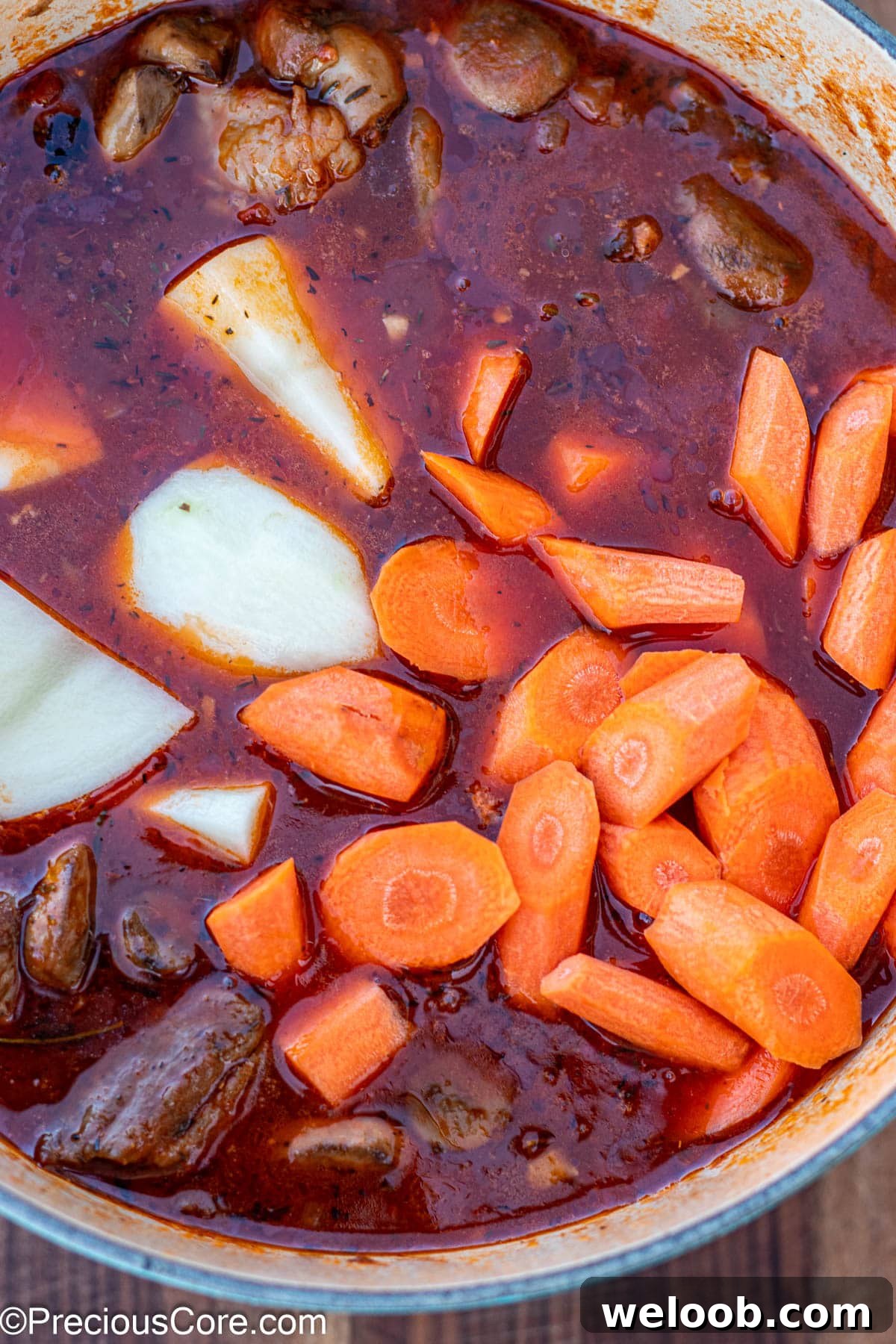 Raw carrots and potatoes added to pot of stew.
