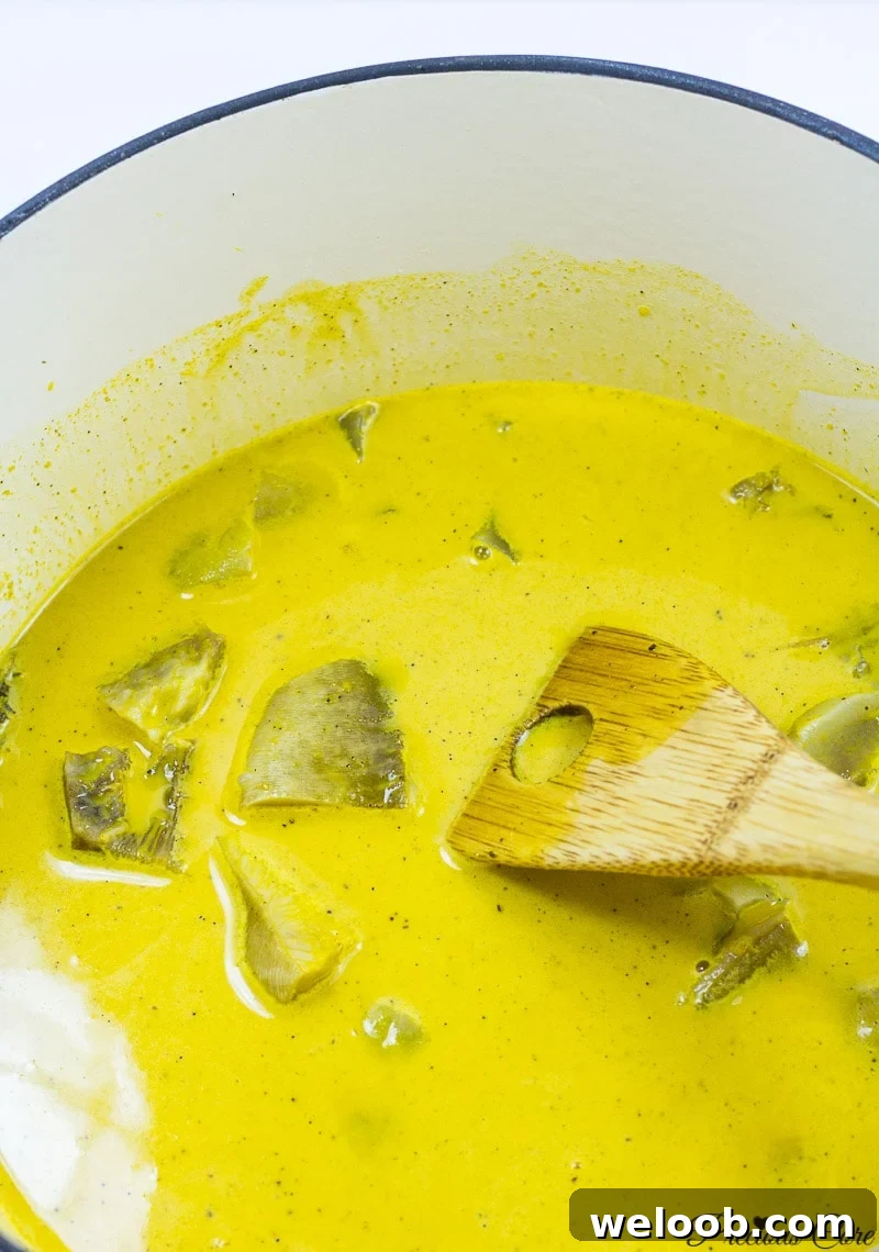 Spatula in a pot of bright yellow Achu Soup.