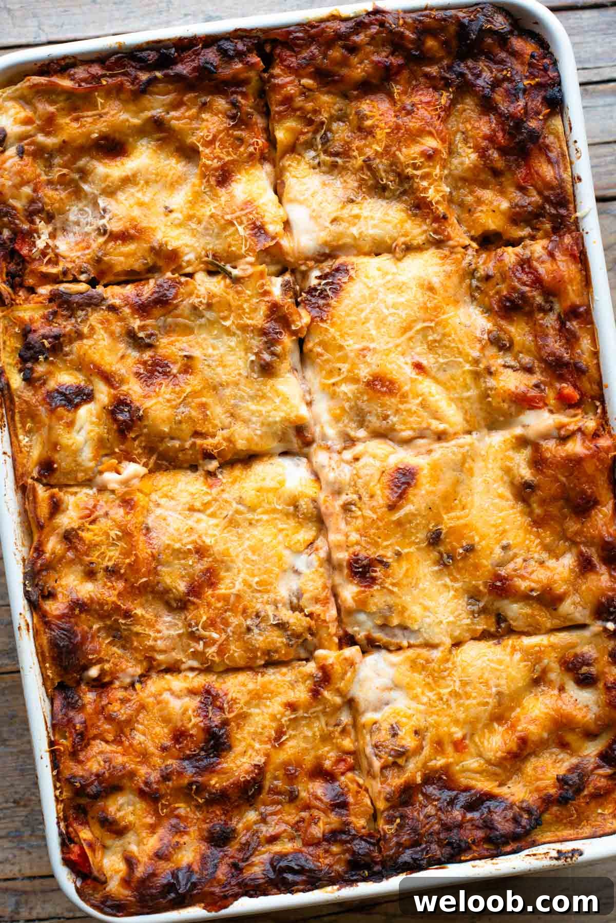 An overhead shot of a lamb lasagna in a large baking dish cut into 8 pieces.