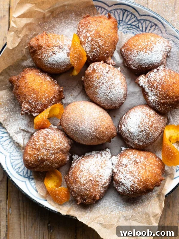 An overhead shot of small ricotta doughnuts on a plate dusted with powdered sugar