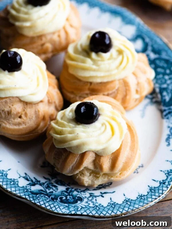 A close up of Italian Zeppole choux buns filled with pastry cream and a cherry on top
