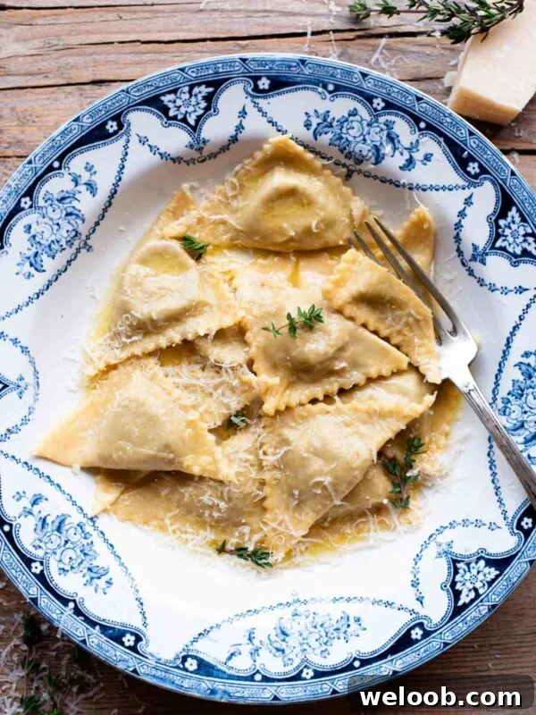 An overhead shot of taleggio and mushroom Triangoli pasta in a blue bowl with a butter sauce.