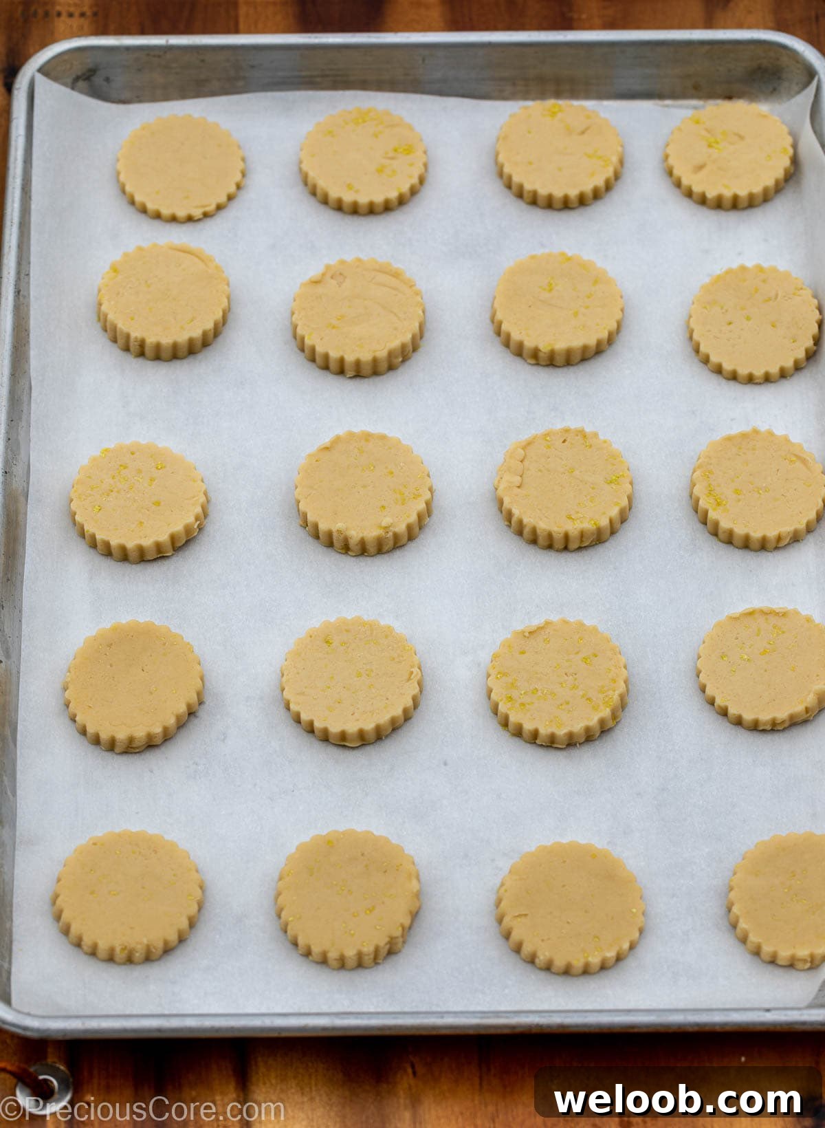 Cut-out cookie dough on baking sheet lined with parchment paper.