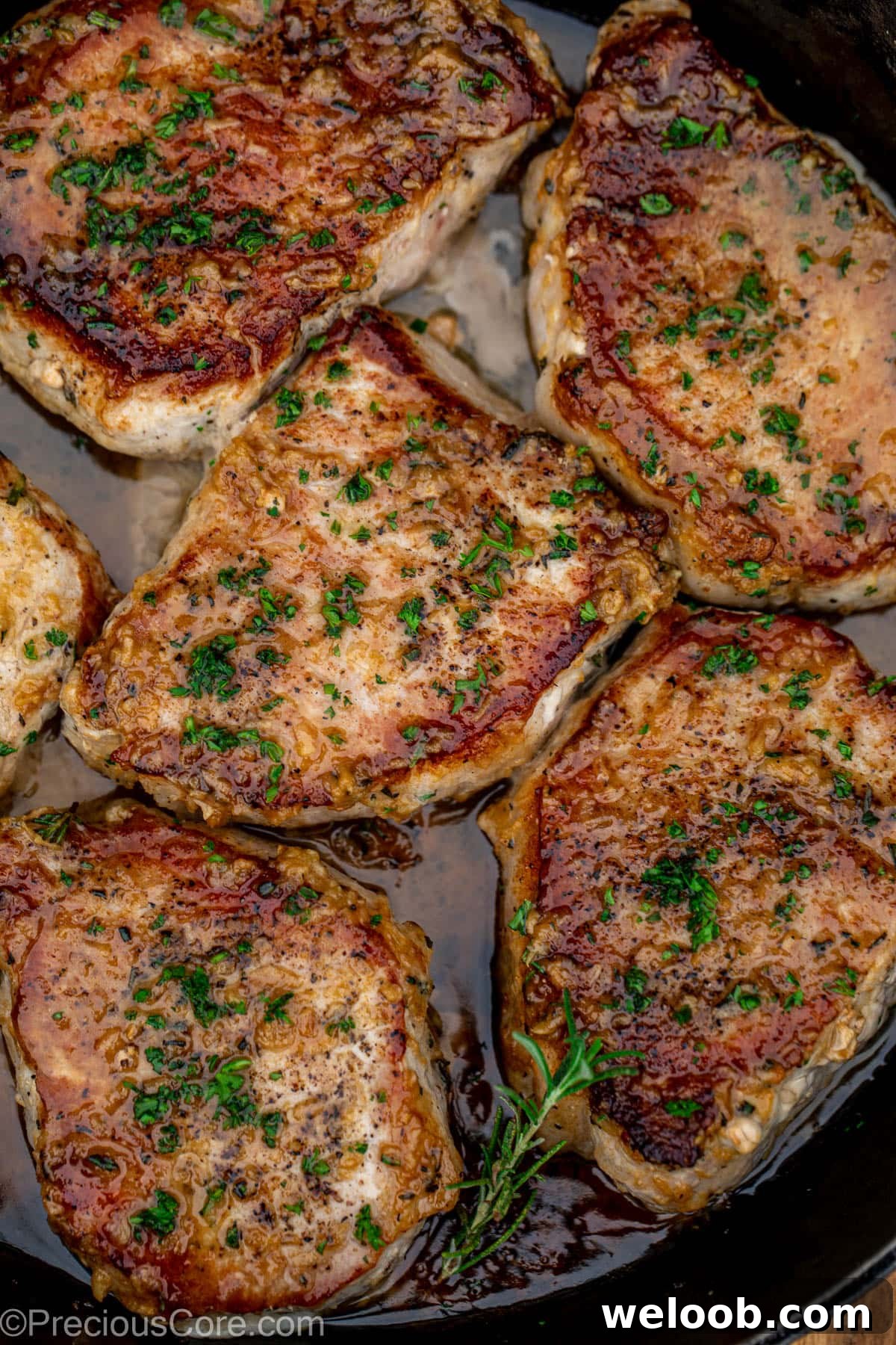 Pan seared boneless pork chops in a cast iron pan with butter underneath.