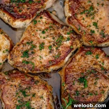 Pan seared boneless pork chops in a cast iron pan with butter underneath.