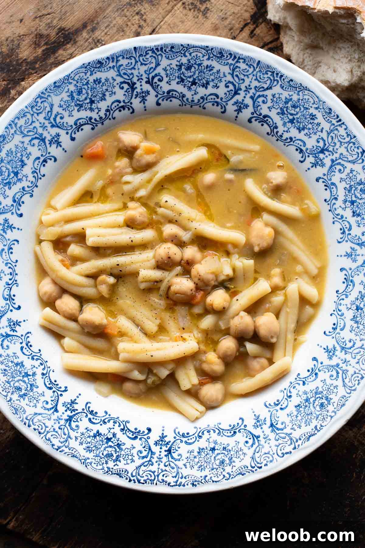 An overhead shot of pasta e ceci (psta and chickpeas) in a blue bowl on a wooden surface.