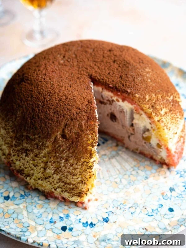 A dome shaped Italian dessert called Zuccotto on a patterned plate with a slice cut out.