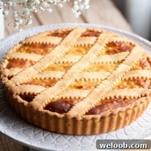A cropped square image of a Pastiera Napoletana (Italian Easter dessert) on a cake stand.