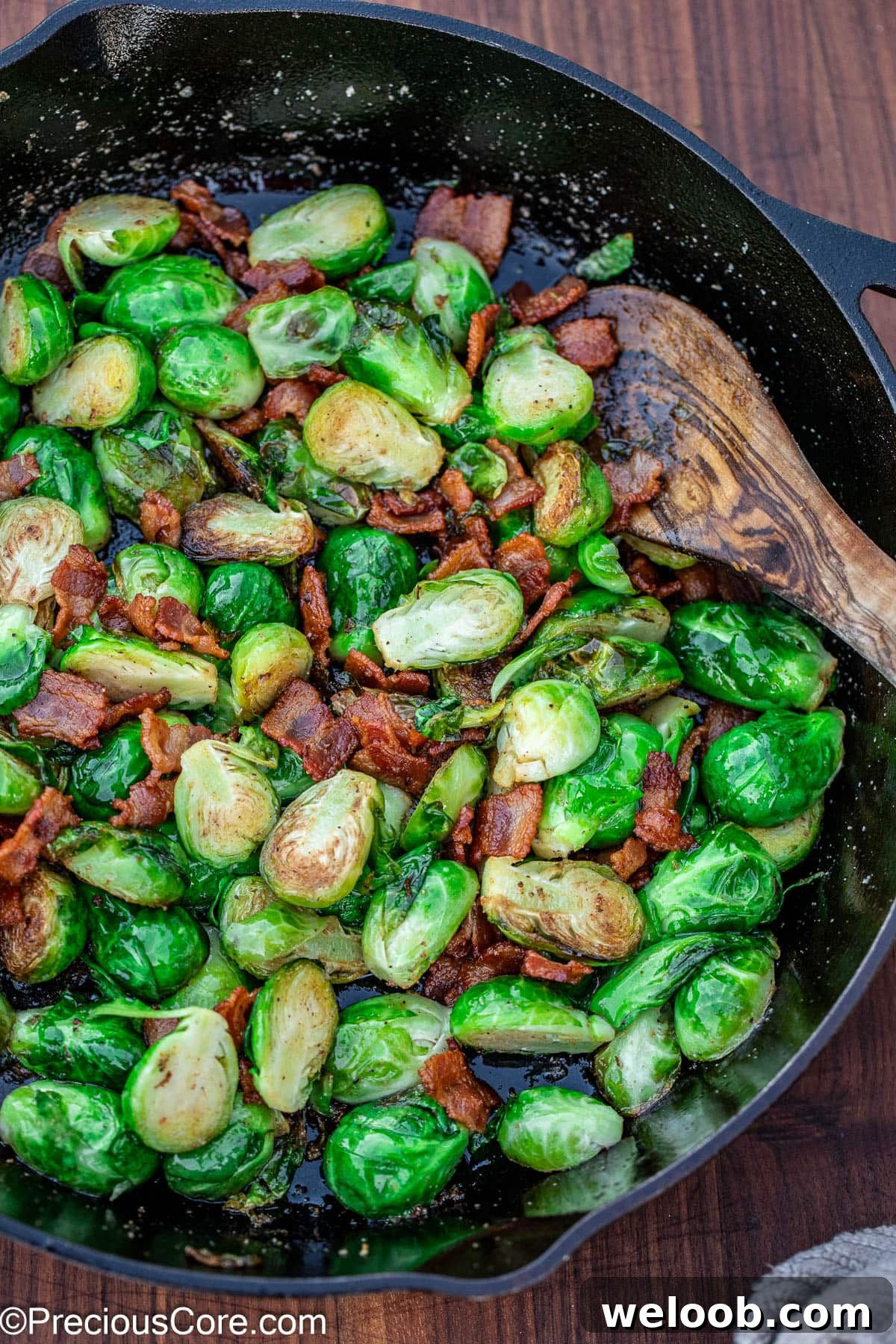 Pan-fried Brussels sprouts with bacon in a black skillet.