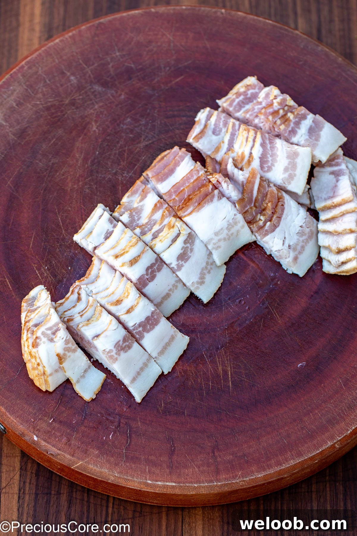 Sliced bacon on a round chopping board.
