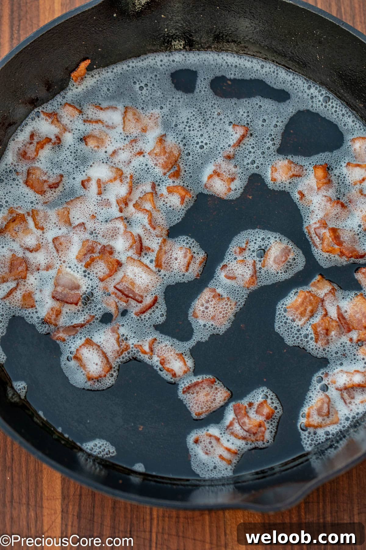 Browned bacon bits in bacon grease in a skillet.