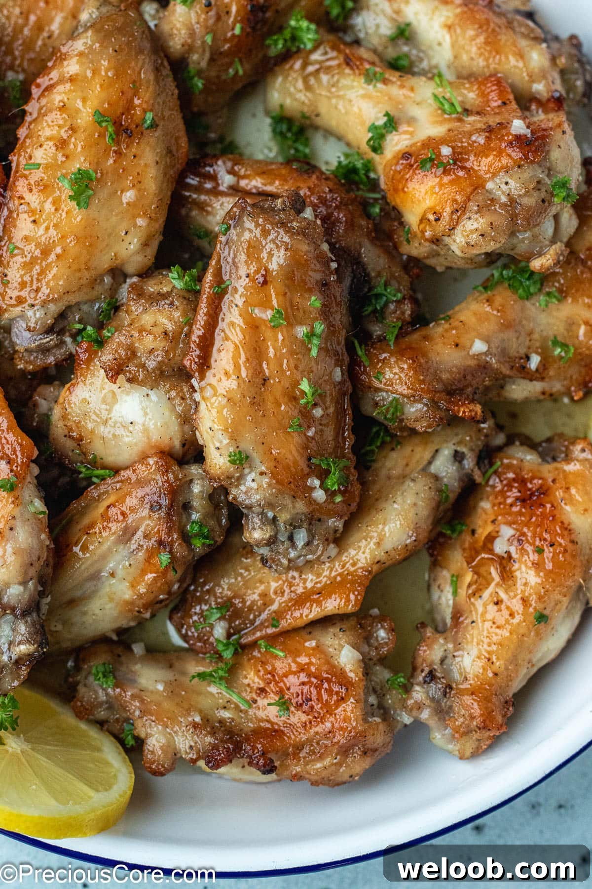 Bowl of chicken wings with garlic butter at the bottom.